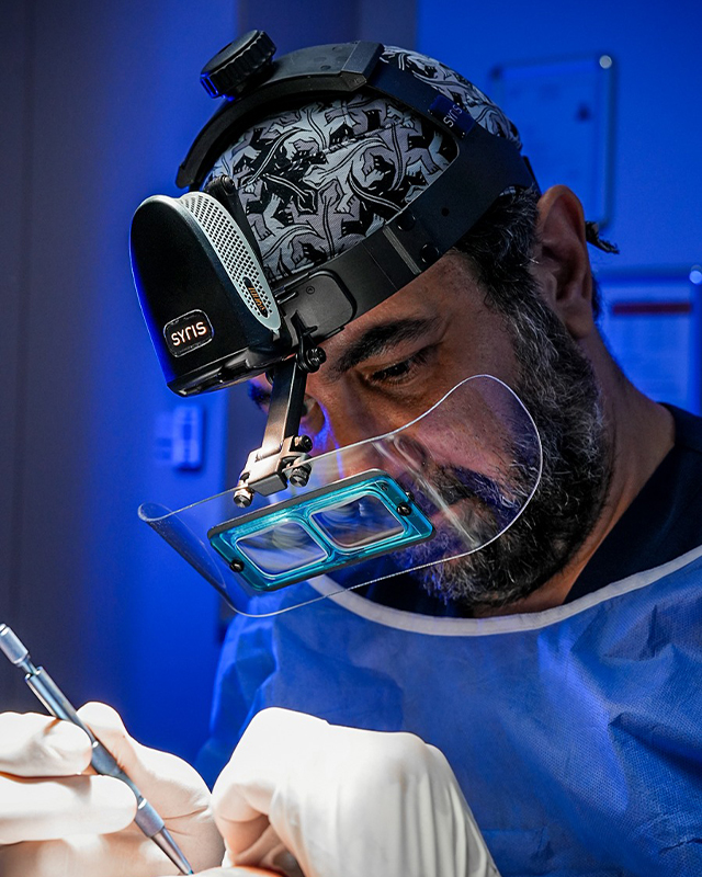 Dr. Emrah Cinik performing a hair transplant with surgical loupes